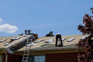 Homeowner inspecting damaged shingles from the ground after a storm.